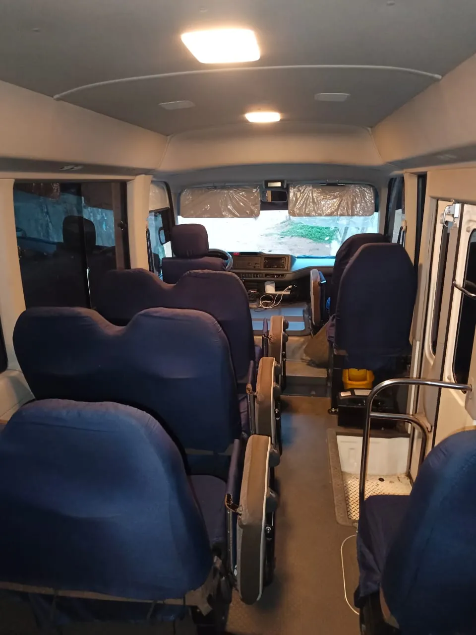 Toyota Coaster interior with blue seat covers, fold-down aisle seats and a view to the front cabin