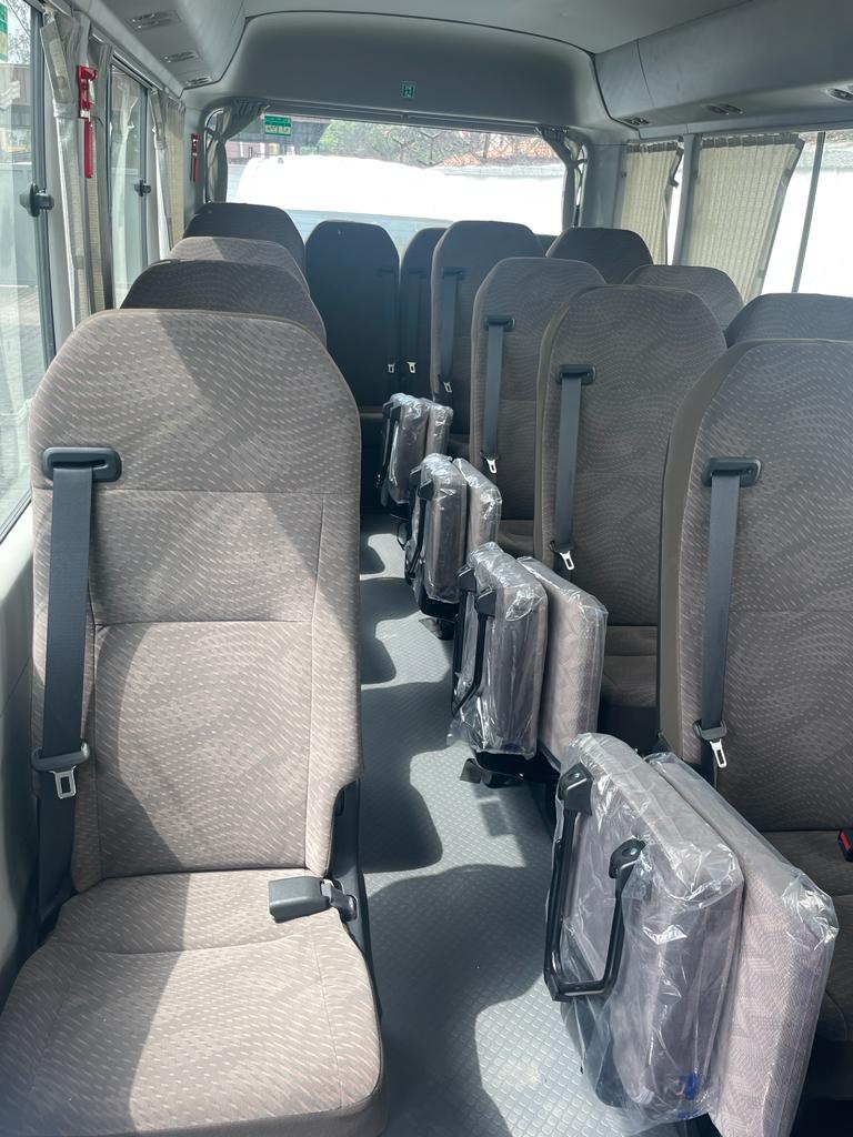 Coaster bus interior showing rows of cloth passenger seats