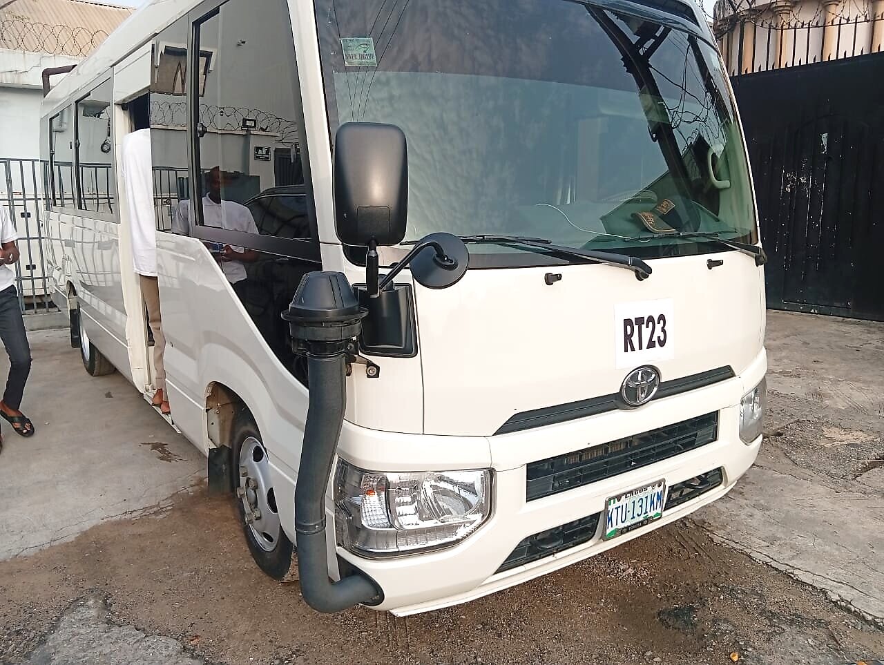 Coaster bus parked with driver boarding through the front door
