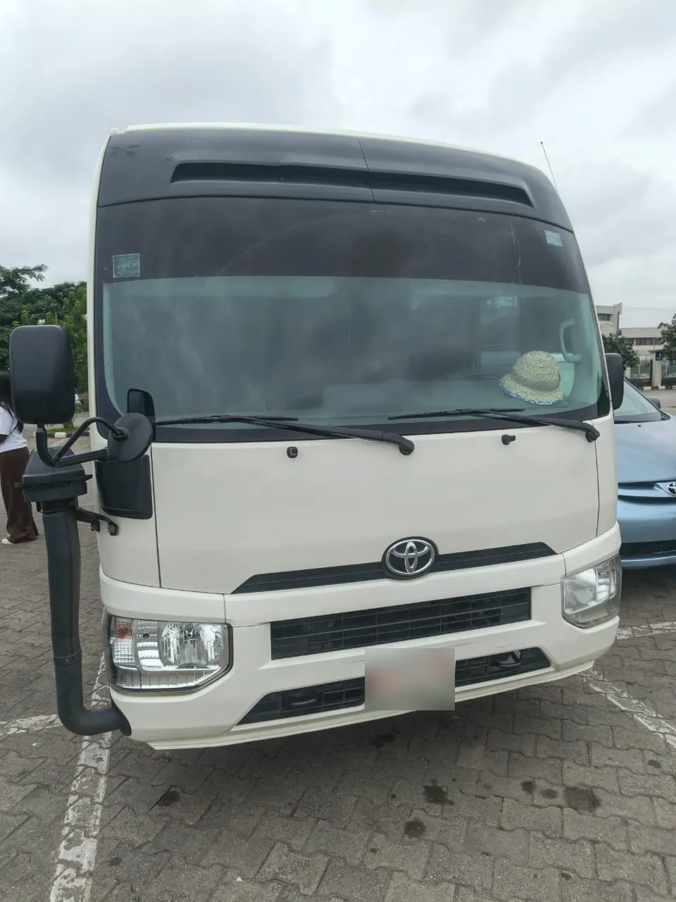 Front view of a white Toyota Coaster bus for hire in Lagos