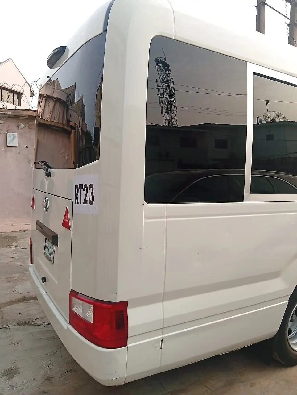 Rear side view of the Coaster bus showing tinted passenger windows