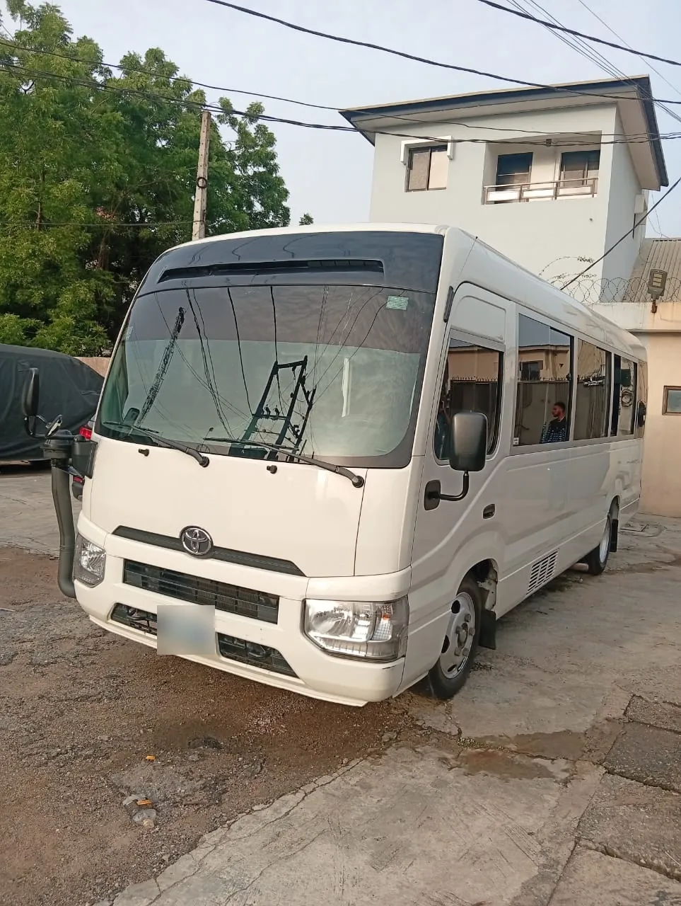 White Toyota Coaster bus for hire in Lagos, front view