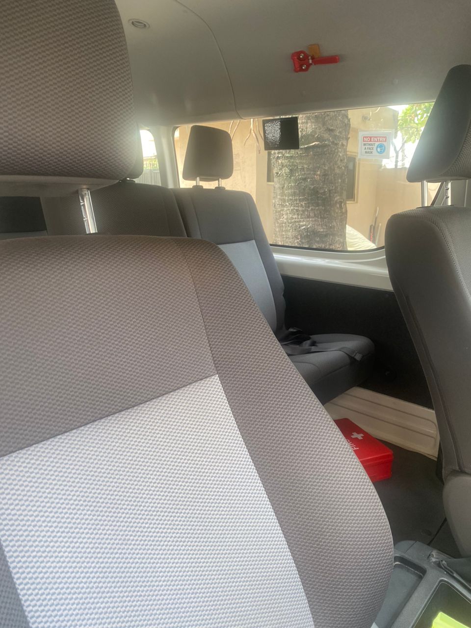 Toyota Hiace interior with grey passenger seats and first-aid kit