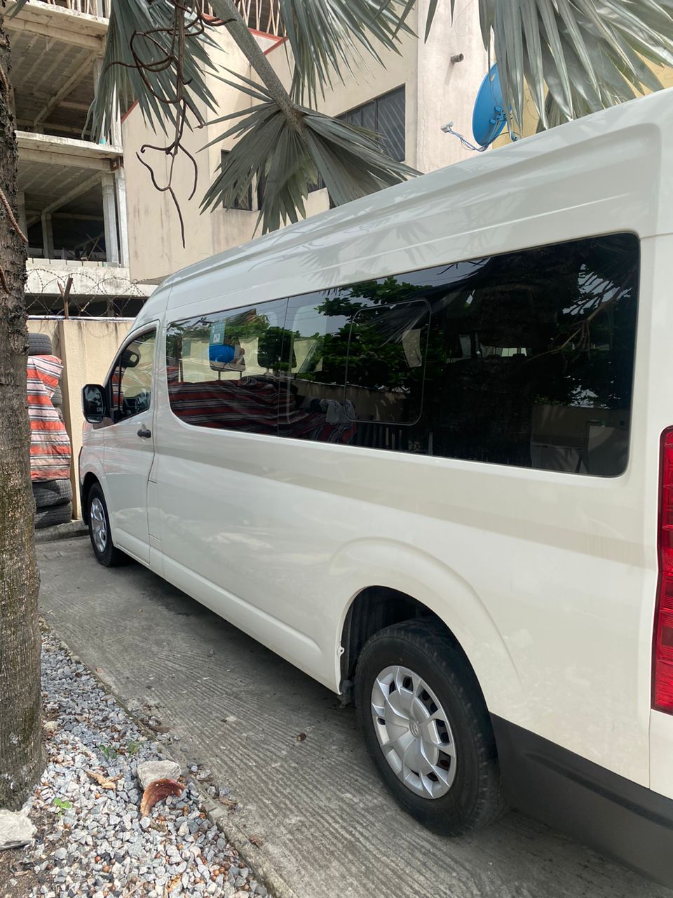 White Toyota Hiace bus parked beside a palm tree in Lagos
