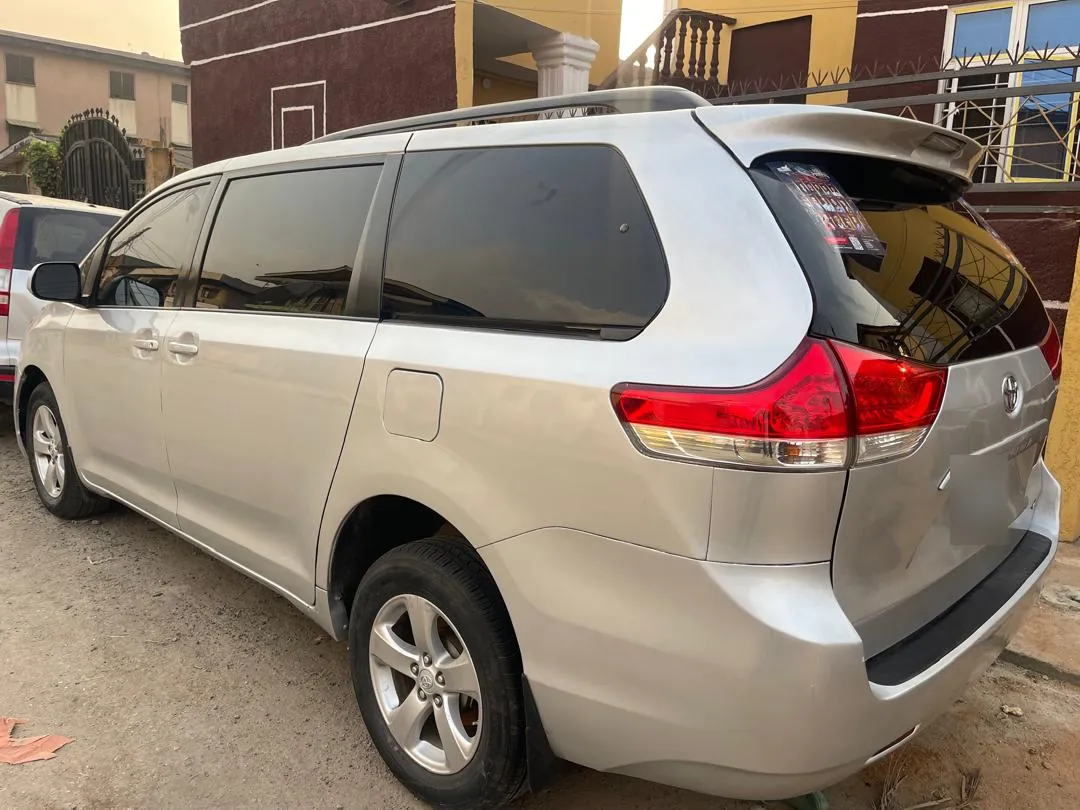 Rear three-quarter view of a silver Toyota Sienna minivan in Lagos